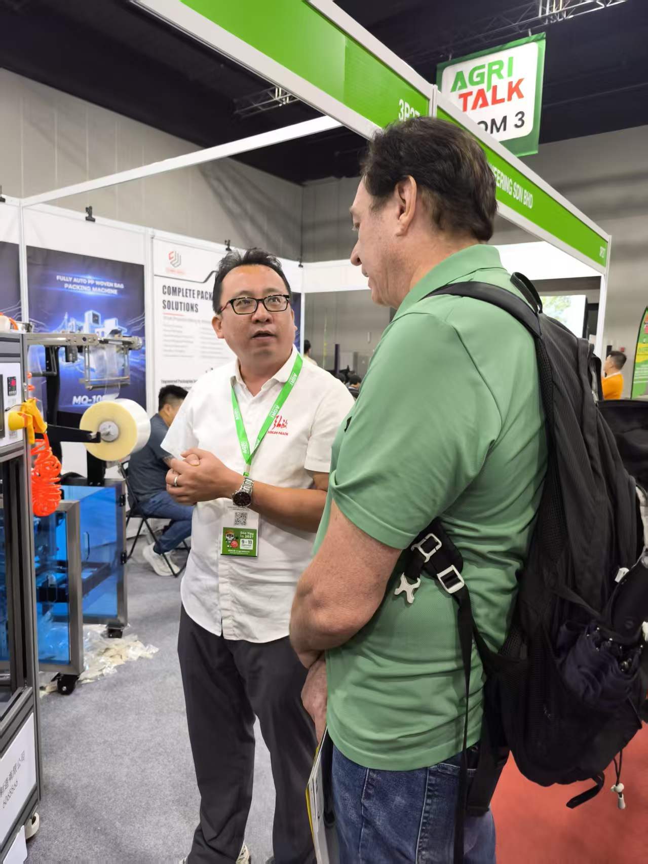 Discussion beside packaging equipment at the Chin Wan booth during Agri Malaysia 2026