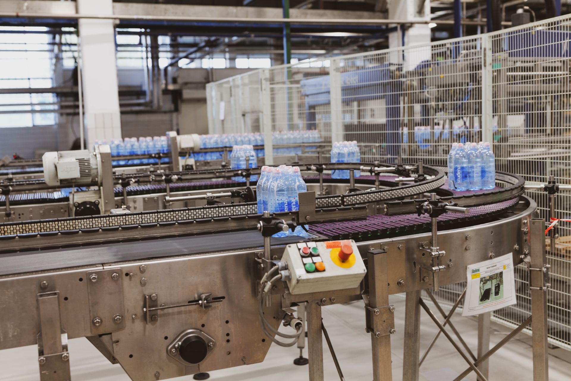 Shrink-wrapped bottled water packs moving along a factory conveyor